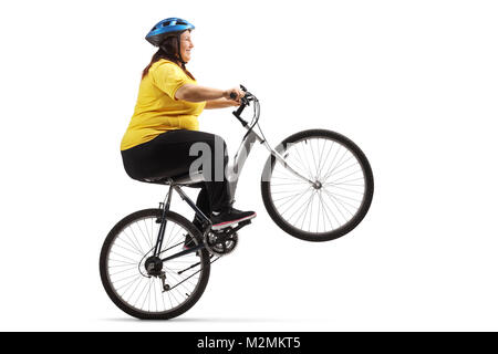 L'excès de woman riding a bike et en faisant un wheelie isolé sur fond blanc Banque D'Images