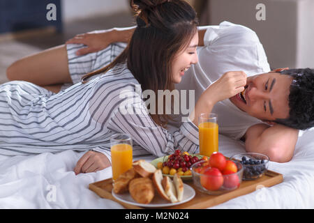 Les jeunes couples ont un petit déjeuner au lit Banque D'Images