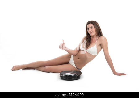 Jeune femme près de l'échelle mécontent de son poids les gestes de tristesse. En forme et en bonne santé. Plus isolé sur fond blanc Banque D'Images