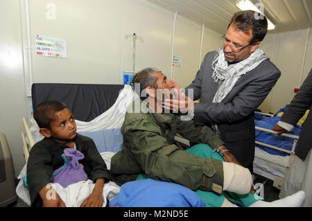 L'Helmand photo gouverneur à 205 (Écossais) hôpital de Camp Bastion, comme il parle à Quadr Abdul et son fils Mohammed Arris la récupération à l'hôpital militaire, voir par lui-même de l'excellence des soins que l'hôpital a à offrir. Date : 16 février 2010 Lieu : Le Camp Bastion (Afghanistan) : 205 Terrain (Écossais) Hôpital de photographe : le Sergent Craig sera l'événement : Le gouverneur de la province de Helmand visiter Crown Copyright Media Ops Camp Bastion, le Helmand Afghanistan Les Forces britanniques Bureau de Poste 715 Téléphone : 0799529916 gouverneur du Helmand au 205 (Écossais) Field Hospital Banque D'Images