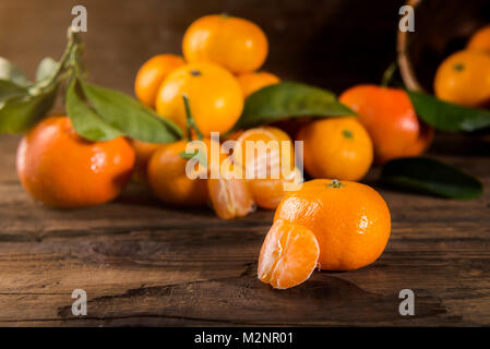 Délicieux et magnifique mini mandarine avec des feuilles sur fond de bois foncé Banque D'Images