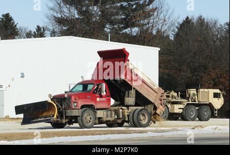 Un opérateur de l'équipement avec le Fort McCoy entrepreneur en déneigement, Kaiyuh Services LLC d'Anchorage, Alaska, les lieux du sable sur une surface glacée, le 30 janvier 2018, à Fort McCoy, au Wisconsin (É.-U. Photo de l'Armée de Scott T. Sturkol, Public Affairs Office, Fort McCoy, Wisconsin) Banque D'Images