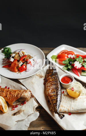 Le maquereau grillé et du bar. Salade de légumes frais. Servir sur une planche en bois sur une table rustique. Restaurant Barbecue menu, une série de photos de différentes viandes poissons anf Banque D'Images