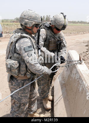 BABIL, de l'Iraq - Capt Elie B. Stamps, chef de peloton avec C Troop, 1er Escadron, 3e régiment de cavalerie blindée observe qu'un câble est correctement verrouillé sur un obstacle sur une route près de site d'exploitation d'Kalsu 17 Juillet. Timbres et son peloton sont chargés de patrouiller dans les zones proches de la base dans un effort pour empêcher les attaques de tir indirect et d'accroître la sécurité de la zone. Photo de l'Armée américaine par le sergent. Garrett Ralston une barrière par United States Forces - Iraq (inactif) Banque D'Images