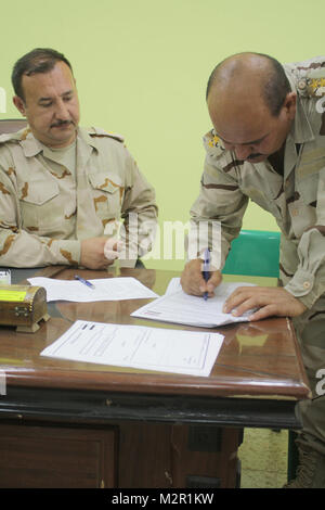 Signer sur la ligne pointillée. SITE D'EXPLOITATION D'URGENCE MAREZ, Iraq - Le Capitaine de l'armée iraquienne Rafool Osow, droit de propriété, pour Al Kisik commande Emplacement signe les documents, de transférer la responsabilité de la station commune de sécurité de l'armée américaine de whisky 4 pour le contrôle de l'armée iraquienne. Les forces américaines créé en 2005 4 JSS Whiskey américain comme une base d'opérations de lutte contre les menaces extrémistes dans la région durant l'opération Iraqi Freedom, et plus récemment, la base a servi de base pour la formation d'unités irakiennes à Al Kisik Base militaire. (U.S. Photo de l'armée par le capitaine Philip Crabtree, 4e AAB PAO, 1st Cav. Div., USD - N) Banque D'Images