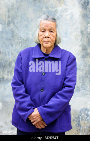 Portrait of senior asian woman standing contre mur vintage Banque D'Images