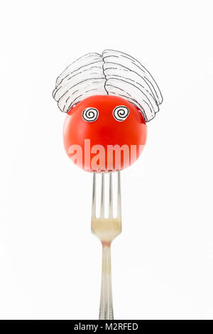 Tomate rouge sur fond blanc avec turban assis comme un fakir sur une fourchette d'argent représentant indien.