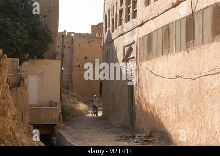 Un homme monté sur son vélo entre les anciennes maisons d'argile dans Al-Hamra, Oman, le 02.10.2017. Dans le monde d'utilisation | Banque D'Images