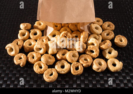 Taralli italiens des craquelins, semblable dans la texture à un longuet ou bretzel et disponibles en saveurs salées ou sucrées, s'échappant d'un sac en papier brun sur Banque D'Images