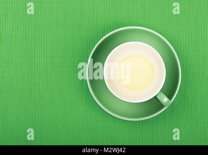 Tasse vide de thé vert clair sur fond vert plus de soucoupe à nappe textile, Close up, augmentation de la vue supérieure Banque D'Images