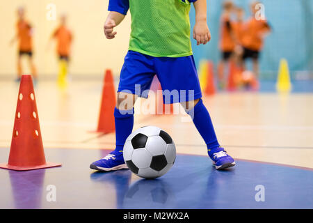 Futsal Football formation pour les enfants. La formation du football dribbles. forage conique Jeune joueur de soccer intérieur avec un ballon de soccer dans une salle de sport. Dvd dans Banque D'Images