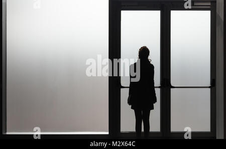 Femme déprimée en attente devant une porte en verre dans une pièce blanche prête à réagir - Maladie - Abus - Concept de phobie Banque D'Images