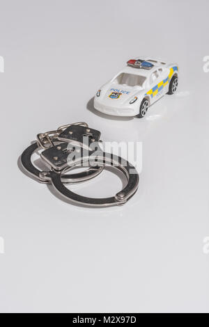 Menottes et jouet voiture de police - comme métaphore de la notion de criminalité. Banque D'Images