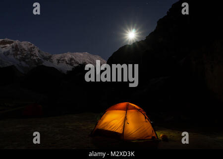 Sous une pleine lune dans un paysage de montagnes avec une orange tente dans l'avant-plan Banque D'Images