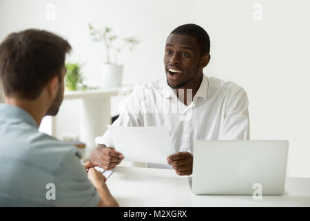 Bonne première impression au concept d'entrevue d'emploi, responsable des ressources humaines de l'Afrique de l'excité impressionné par les réalisations de carrière à reprendre des candidats de race blanche, noire em Banque D'Images