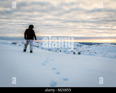 Seul homme marchant dans la neige dans le désert au lever du soleil Banque D'Images