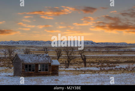 Une maison en bois carrés abandonnés avec des fenêtres cassées dans une vallée avec des canyons à l'arrière-plan dans un coin de campagne en hiver paysage Wyoming Banque D'Images