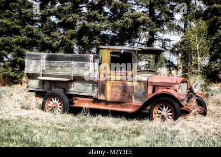 Une friche vintage Années 1830 rusty camion avec boîte en bois en assez bon état parqué par une forêt d'arbres Banque D'Images