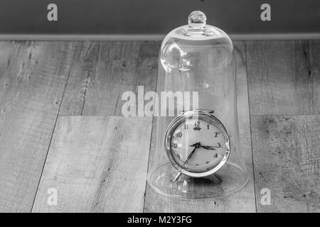 Concept de gestion du temps : Close up red vintage réveil être déformés ou endommagés sur le plancher en bois dans le dôme de verre. Banque D'Images