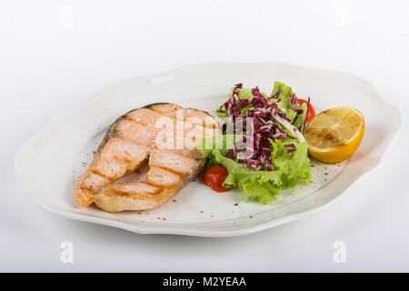 Pavé de saumon poêlé avec salade et citron sur une plaque blanche isoler Banque D'Images