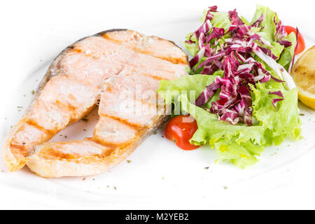 Pavé de saumon poêlé avec salade et citron sur une plaque blanche isoler. close up Banque D'Images