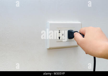 Sortie main main d'économie d'insertion dans la prise électrique murale Banque D'Images