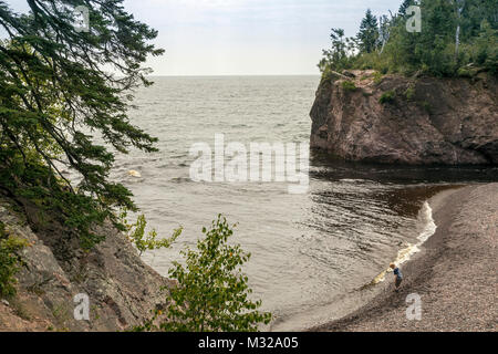 Silver Bay, Minnesota - un garçon sur la rive du lac Supérieur, où la rivière entre dans le Baptême, dans le lac Tettegouche State Park. Banque D'Images