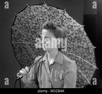 Jeune femme modèles avec un parapluie en studio, ca. 1945. Banque D'Images