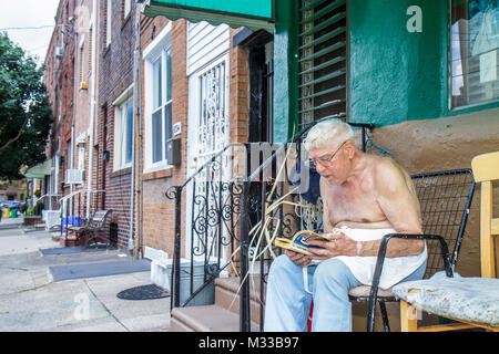 Philadelphie Pennsylvania,South Philly,Street,trottoir,homme hommes,senior seniors citoyens,barechiste,assis,lecture,cheveux blancs,extérieur,rangée h Banque D'Images