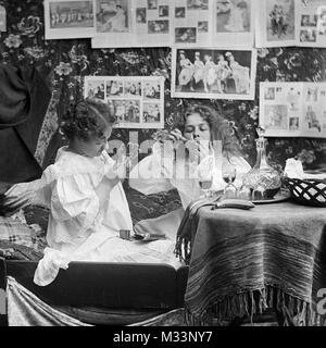 Deux jeunes femmes boire et fumer au lit, ca. 1910. Banque D'Images