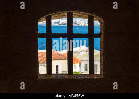 Vue depuis la sombre cellule de prison. Détail d'une fenêtre avec grille en fer forgé (grill) Château et vue sur la mer bleue d'un ancien château. Banque D'Images