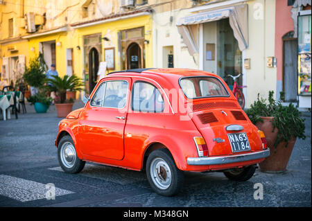 ISCHIA, ITALIE - CIRCA Octobre 2017 : rouge tomate vintage emblématique Fiat 500 voiture garée sur l'harbourside. Banque D'Images