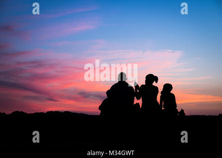 Silhouette d'une famille jouissant d'un magnifique coucher de soleil Banque D'Images
