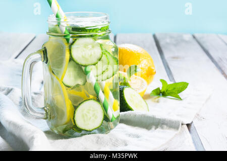 L'eau douce de l'été avec detox citron, concombre, menthe et glace en pot Mason sur un fond de bois blanc. Banque D'Images