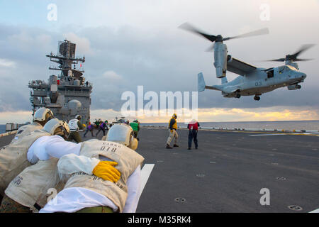160125-N-IK388-046 OCÉAN PACIFIQUE (jan. 25, 2016) Les Marines affectés à la lutte contre les marchandises à bord du navire d'assaut amphibie USS Bonhomme Richard (DG 6) le vent comme une MV-22 Osprey attaché à rotors basculants moyen maritime (VMM) de l'Escadron 265 (renforcée) atterrit sur le poste de pilotage. Bonhomme Richard est le premier navire du Bonhomme Richard Groupe amphibie et est l'avant-déployés dans la 7ème Flotte américaine zone d'exploitation. (U.S. Photo par marine Spécialiste de la communication de masse 2e classe Stacy M. Atkins Ricks/relâché), Opérations de vol, USS Bonhomme Richard par # PACOM Banque D'Images