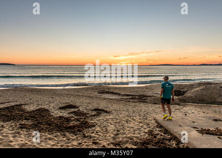 Un homme commence à exercer au coucher du soleil sur la Playa de Palma, Palma de Mallorca, Majorque, Espagne. Banque D'Images