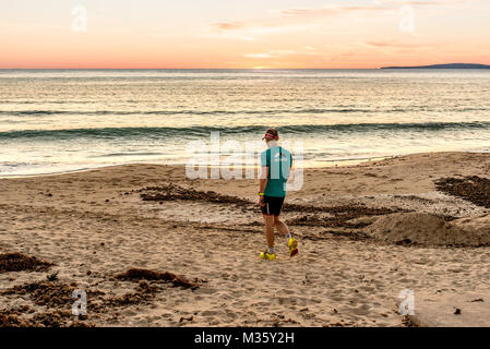 Un homme commence à exercer au coucher du soleil sur la Playa de Palma, Palma de Mallorca, Majorque, Espagne. Banque D'Images