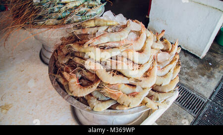 Dubaï, Émirats arabes unis - circa 2010 : tilt-MCU jusqu'à des tas de poisson frais affichés sur des béquilles à un marché aux poissons. Les poissonniers en uniformes bleus travaillent sur le poisson Banque D'Images