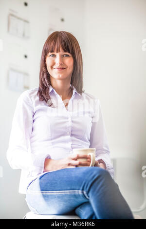 Portrait of beautiful young businesswoman holding Coffee cup in office Banque D'Images