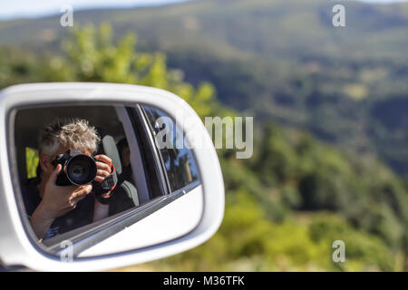 Self Portrait dans un rétroviseur d'une voiture à l'arrière-plan du paysage. Banque D'Images