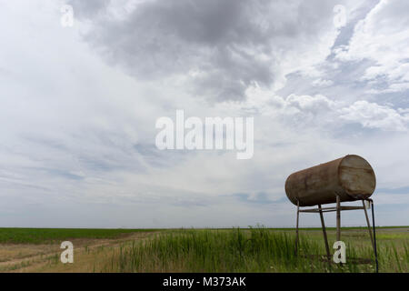 Ancien réservoir d'eau rouillée et le baril sur les plaines sous un ciel blanc laiteux Banque D'Images