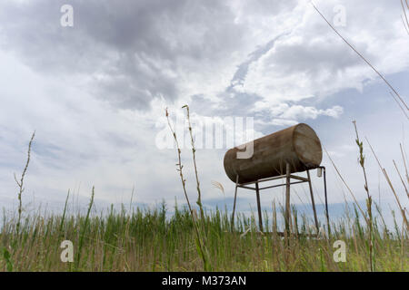 Ancien réservoir d'eau rouillée et le baril sur les plaines sous un ciel blanc laiteux Banque D'Images