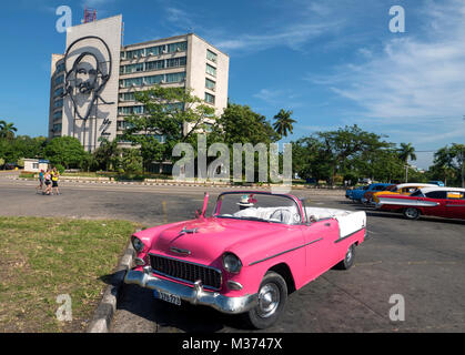 1955 Chevrolet Bel Air rose convertible dans la place de la Révolution, La Havane avec fresque de Fidel Castro sur la construction en arrière-plan. Banque D'Images