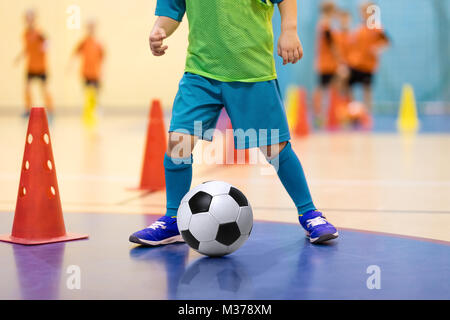 Futsal Football formation pour les enfants. La formation du football dribbles. forage conique Jeune joueur de soccer intérieur avec un ballon de soccer dans une salle de sport. Dvd dans Banque D'Images