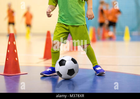 Futsal Football formation pour les enfants. La formation du football dribbles. forage conique Jeune joueur de soccer intérieur avec un ballon de soccer dans une salle de sport. Dvd dans Banque D'Images