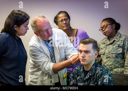 Ancien colonel de l'Armée de l'air, le Dr Stephen Burns démontre l'application d'un champ de bataille de l'aiguille d'Acupuncture sur l'oreille de l'hôpital de la Marine Logan Corpsman Badders comme infirmière praticienne Melanie Medina et des infirmières autorisées Sylvia L Brooks et Air Force 1er lieutenant Folake Niniola observer au cours d'une séance de formation à l'Acupuncture de bataille l'Armée de l'air Centre d'Acupuncture à la Malcolm croître clinique médicale, Joint Base Andrews, Md., Jun. 21, 2017. (U.S. Air Force photo par J.M. Eddins Jr.) 20170621-F-LW859-015 par AirmanMagazine Banque D'Images