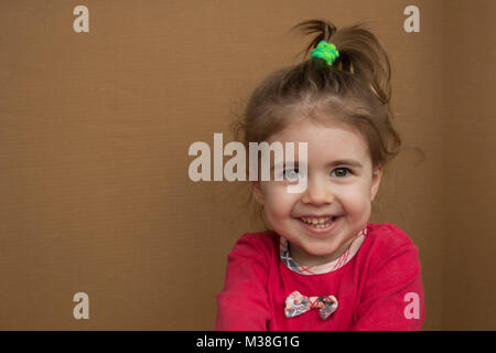 Clouse-up portrait of smiling little girl sur le fond d'une boîte en carton Banque D'Images