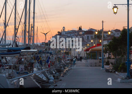 Coucher du soleil dans la ville de Poros avec stern à quay yachts amarrés dans l'avant-plan et de maisons blanches à l'arrière-plan Banque D'Images