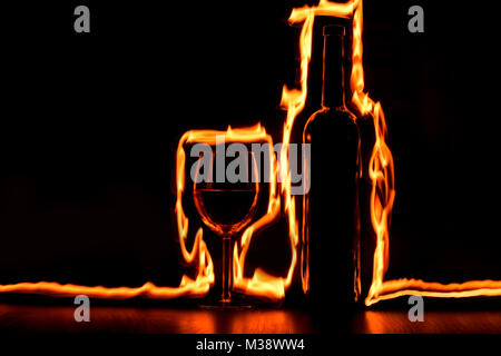 Jouer avec le feu des traces autour du verre et bouteille de vin. Banque D'Images