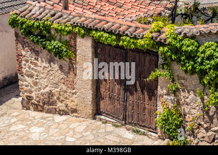 Porte en bois rustique avec un petit toit et d'un lierre sur un mur d'une maison dans une ville dans la province de Madrid. L'Espagne. Banque D'Images